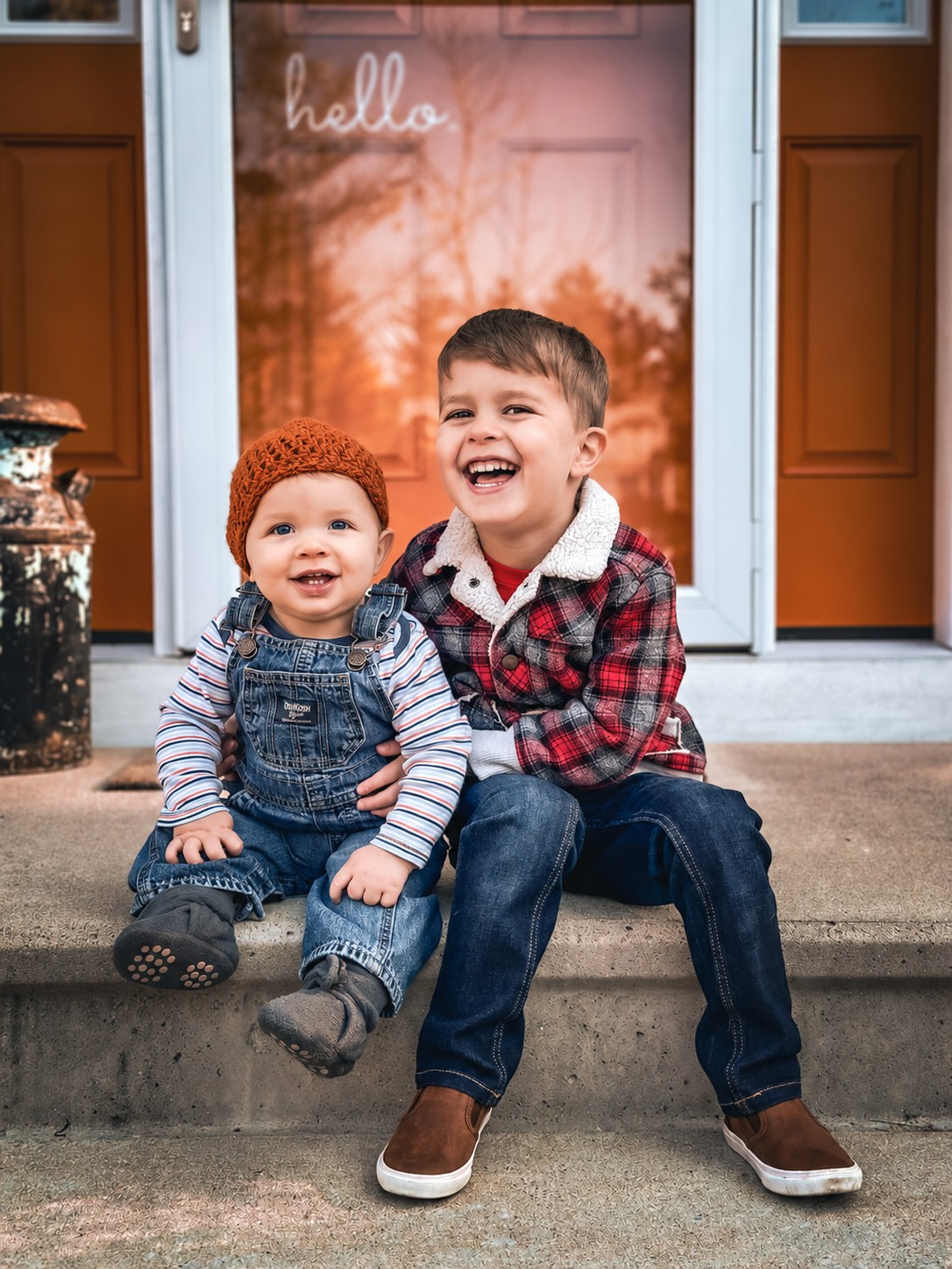 Two brothers laughing together on a porch step in front of a door