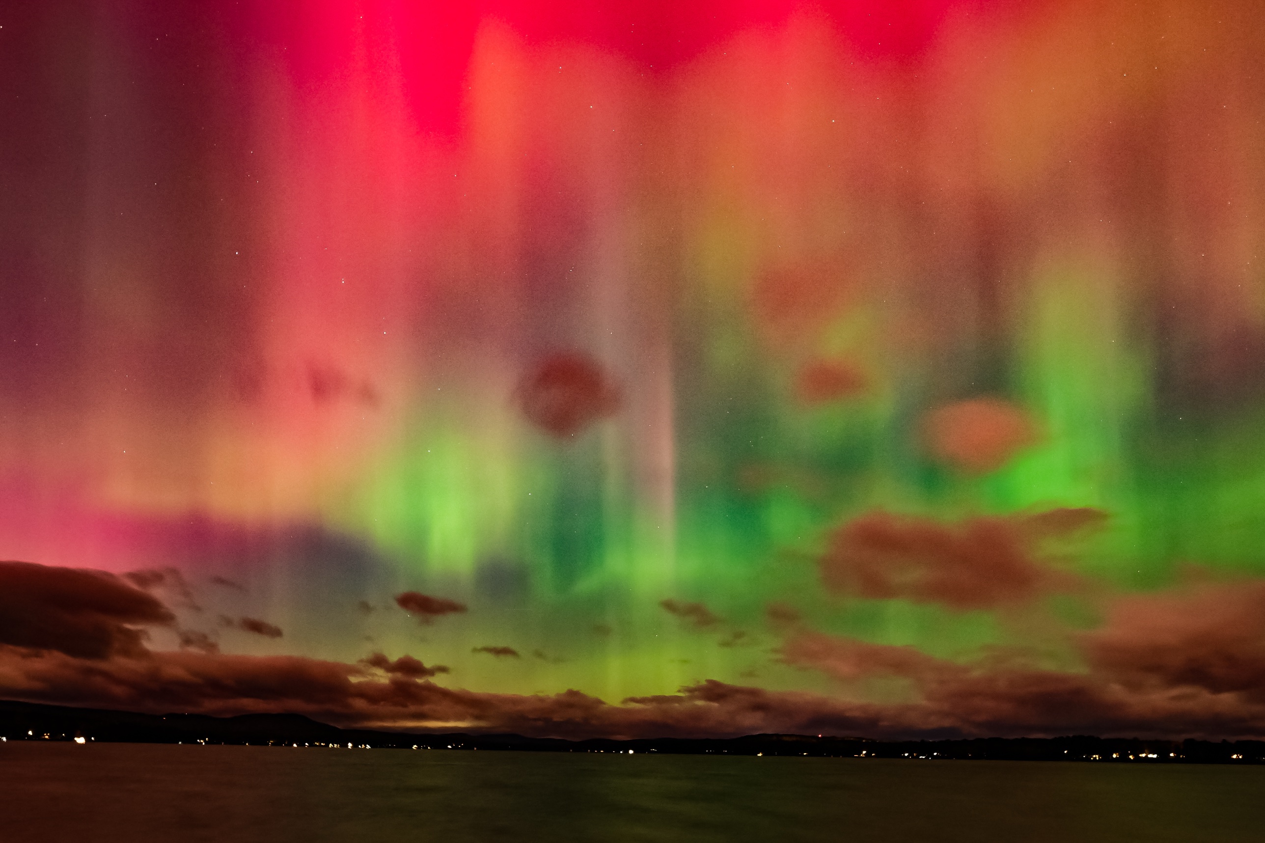 Vivid red, pink, and green aurora beams over Lake Winnisquam, New Hampshire