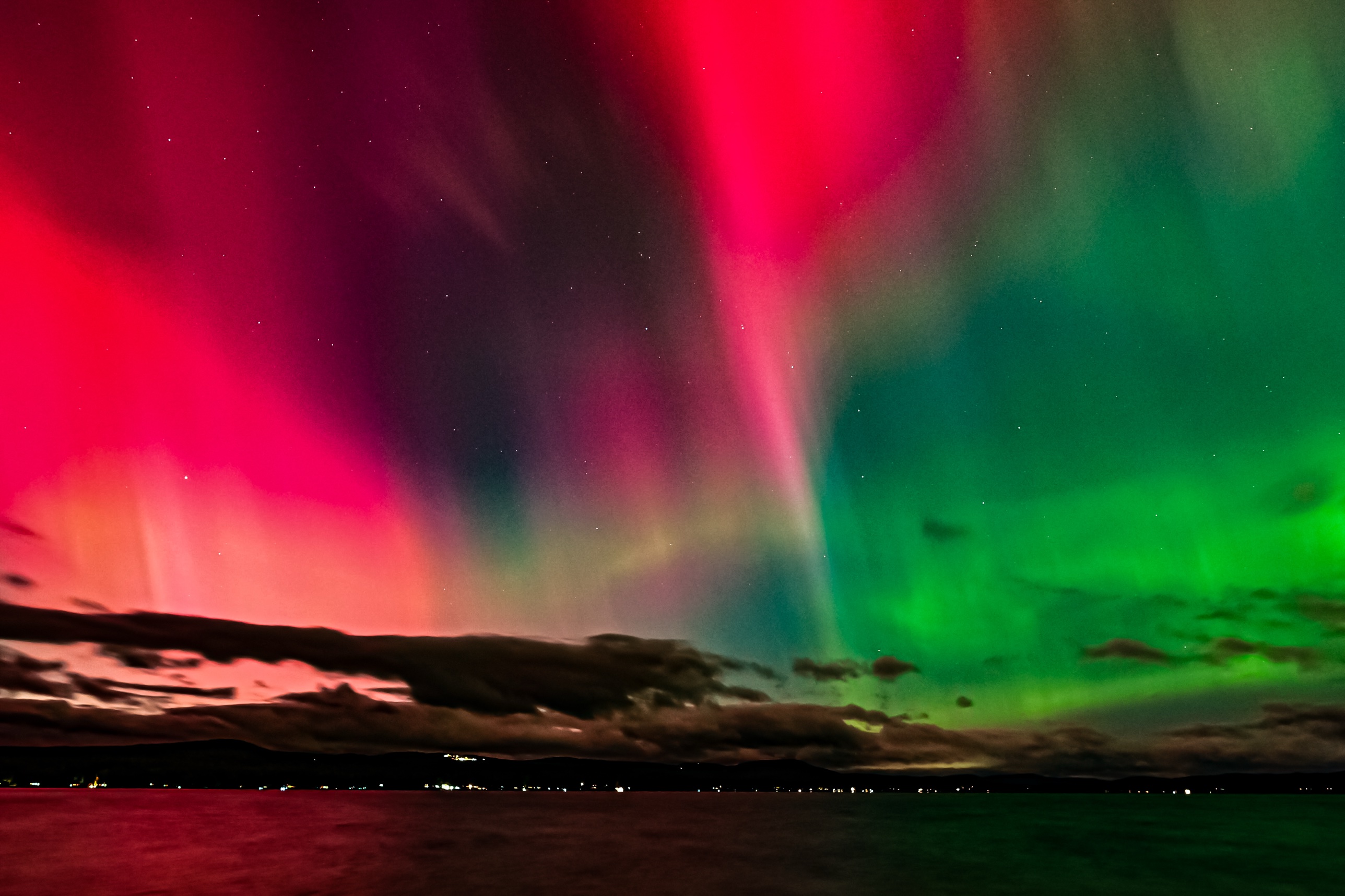 A wide band of pink, red, and green aurora over Lake Winnisquam, New Hampshire