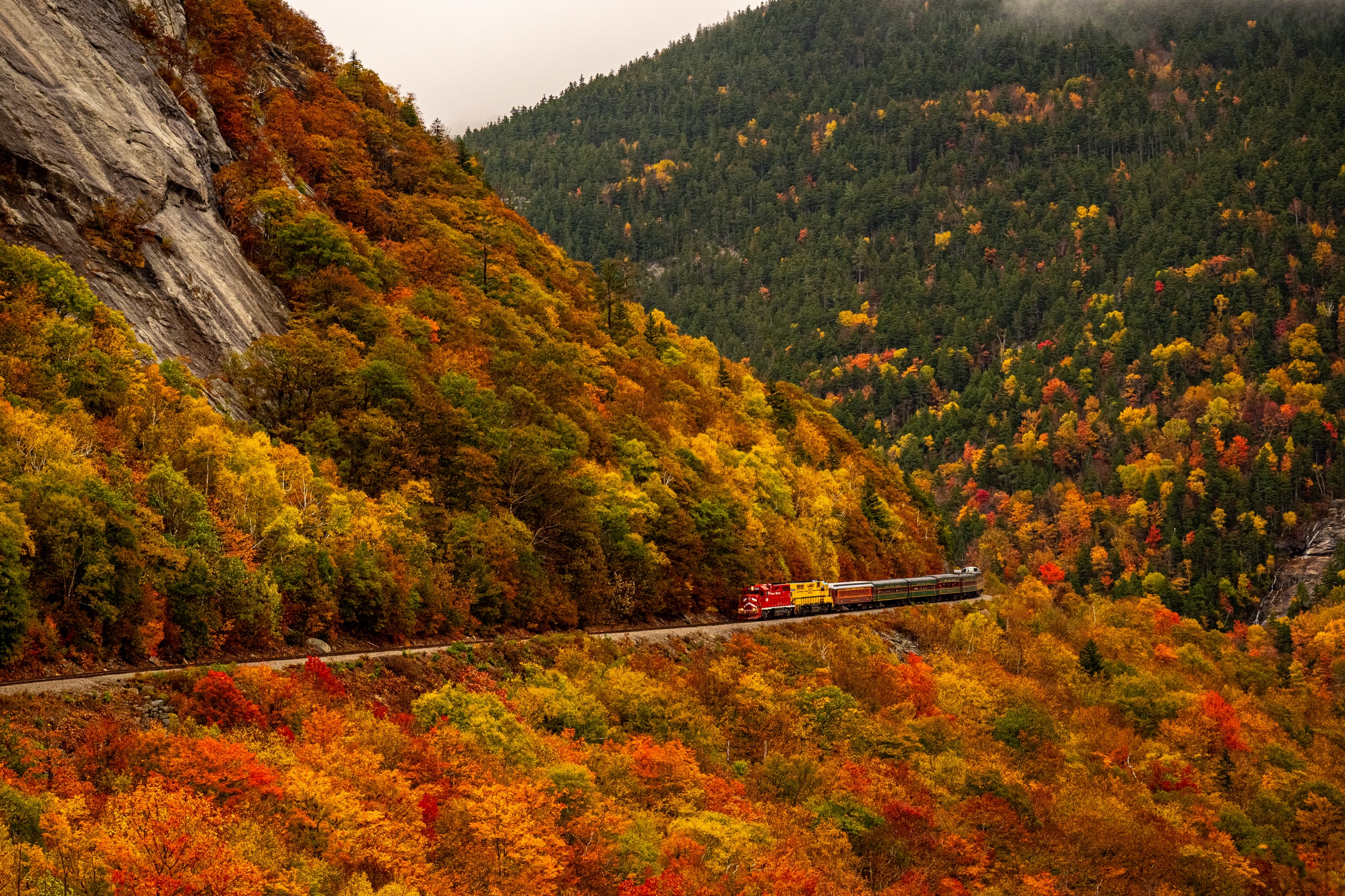 The Conway Scenic Railroad crossing a trestle through peak foliage in Crawford Notch, New Hampshire