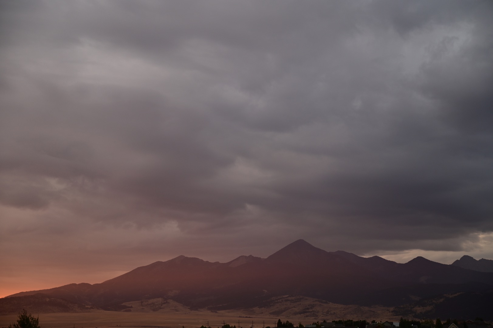 A mountain range in Montana glowing at dusk beneath heavy clouds